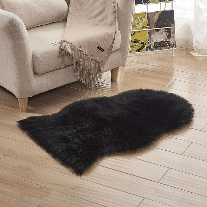 Plush carpet floor mat placed in a bedroom near the bed on a wooden floor