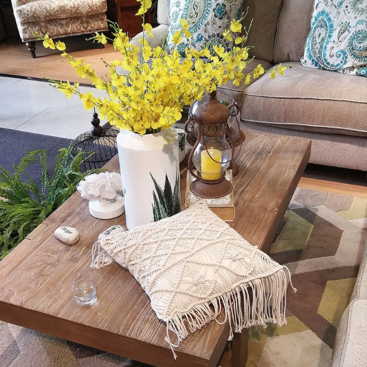 Hand-woven macrame cotton cushion cover on a rustic wooden bench with boho décor