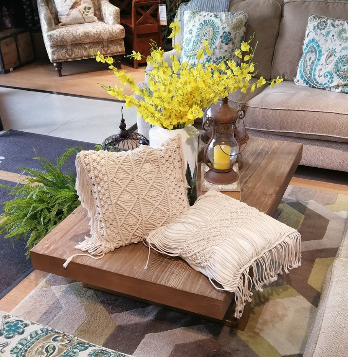 Hand-woven macrame cotton cushion cover on a rustic wooden bench with boho décor