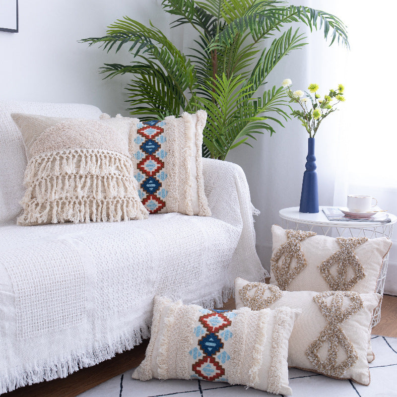 Tufted Moroccan fringed waist pillow on a boho-style sofa with cozy textures