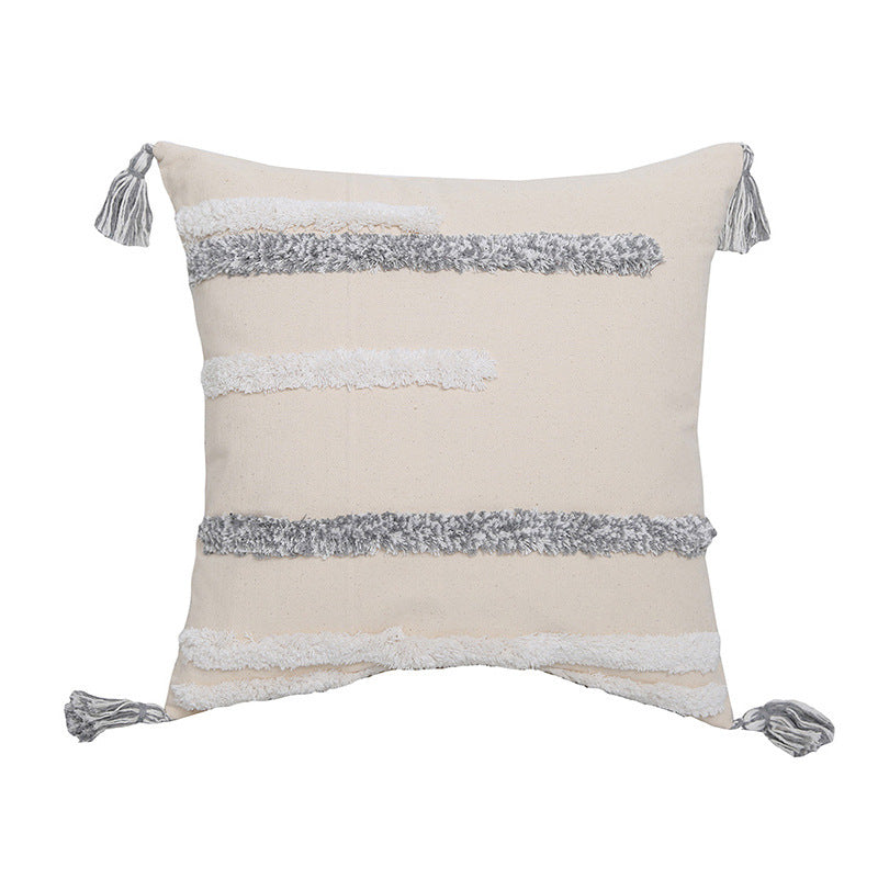 Hand-embroidered tufted pillowcase with fringe on a cozy sofa in a rustic living room