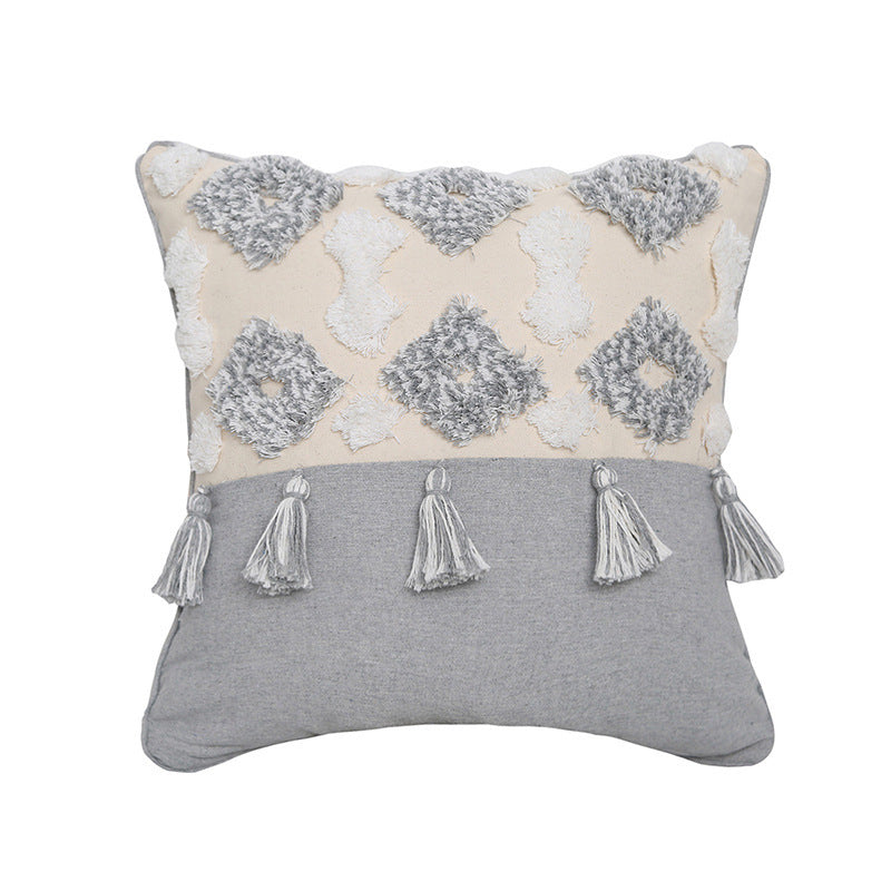 Hand-embroidered tufted pillowcase with fringe on a cozy sofa in a rustic living room
