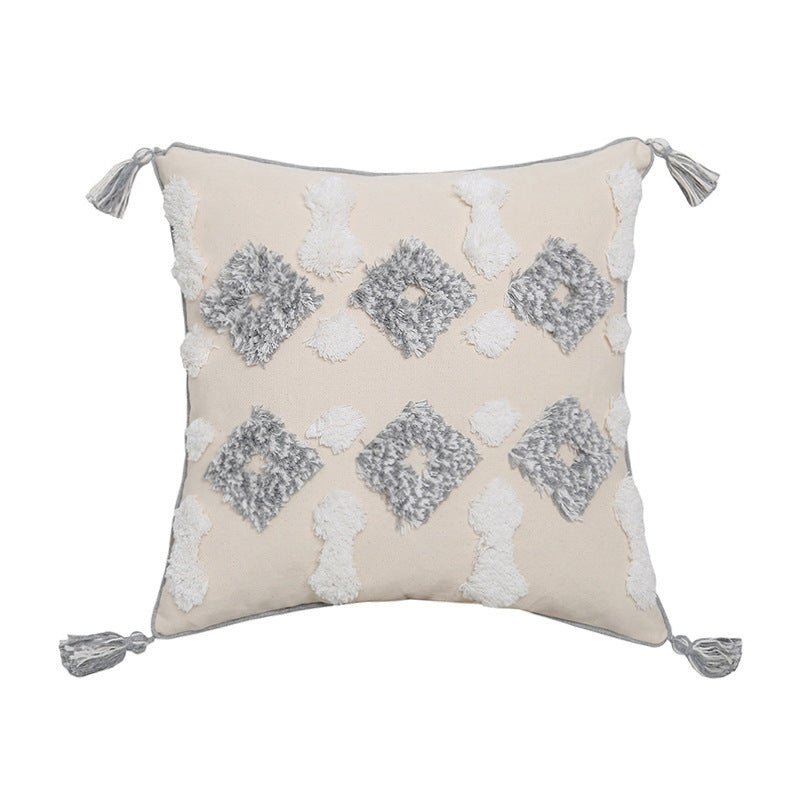 Hand-embroidered tufted pillowcase with fringe on a cozy sofa in a rustic living room