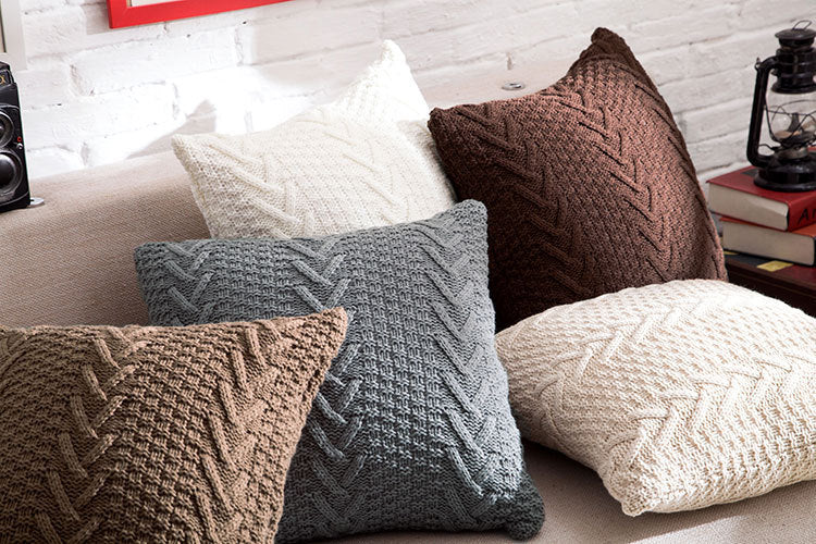 Thick wool knitted pillowcase with chunky knit pattern on a cozy sofa

