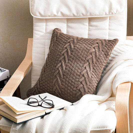 Thick wool knitted pillowcase with chunky knit pattern on a cozy sofa

