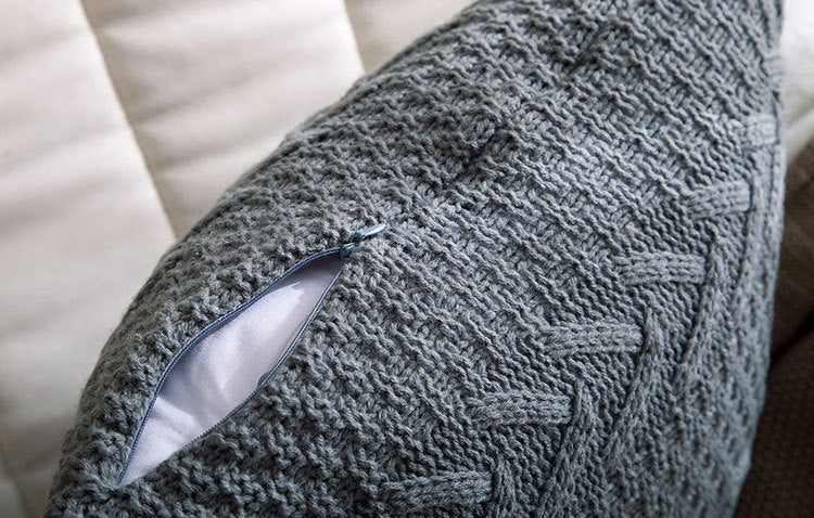 Thick wool knitted pillowcase with chunky knit pattern on a cozy sofa

