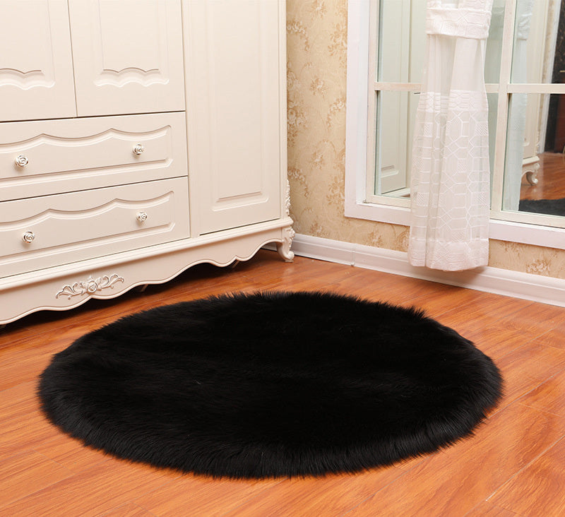 Round faux sheepskin white rug placed beside a bed on a wooden floor in a cozy bedroom

