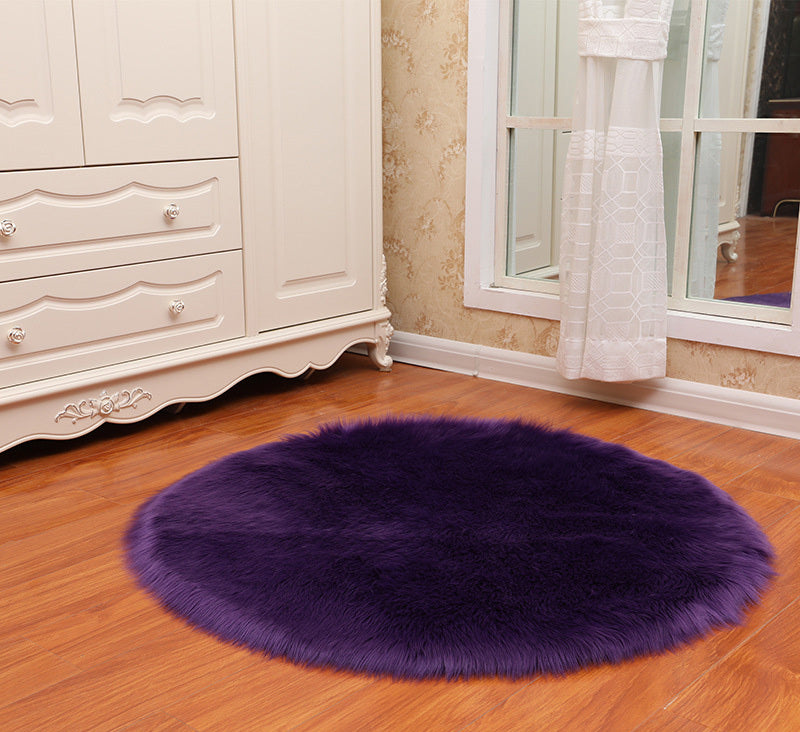 Round faux sheepskin white rug placed beside a bed on a wooden floor in a cozy bedroom


