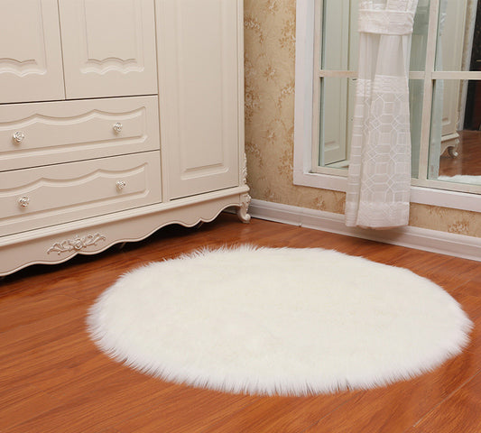 Round faux sheepskin white rug placed beside a bed on a wooden floor in a cozy bedroom

