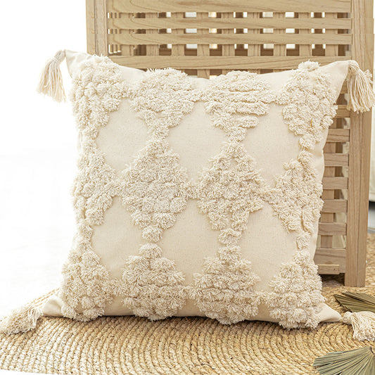 Tufted throw pillow with tassels placed on a cozy sofa in a boho-styled living room



