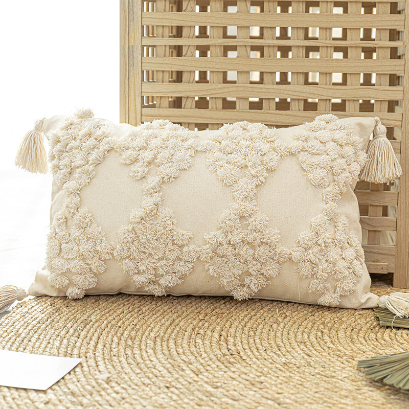 Tufted throw pillow with tassels placed on a cozy sofa in a boho-styled living room

