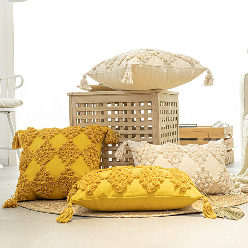 Tufted throw pillow with tassels placed on a cozy sofa in a boho-styled living room

