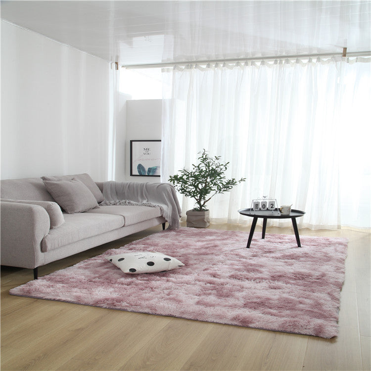 Tie-dye gradient rug with long wool texture beside a bed and end table in a modern bedroom

