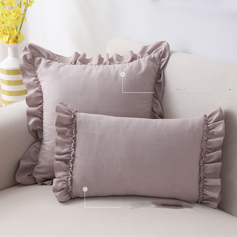 Small suede cushion pillowcase placed on a sofa beside a neutral-toned bed setup

