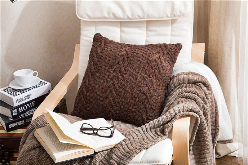 Thick wool knitted pillowcase with chunky knit pattern on a cozy sofa

