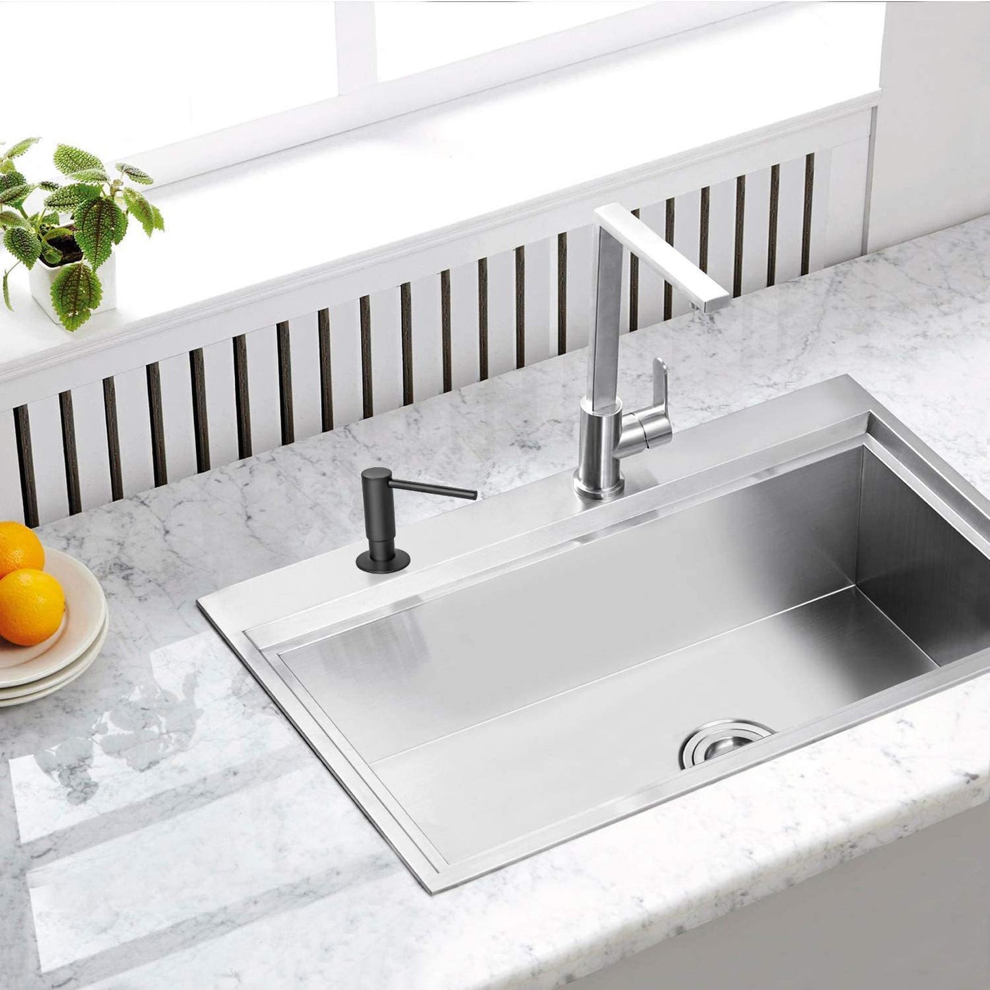 Stainless steel kitchen sink with black faucet on a marble countertop
