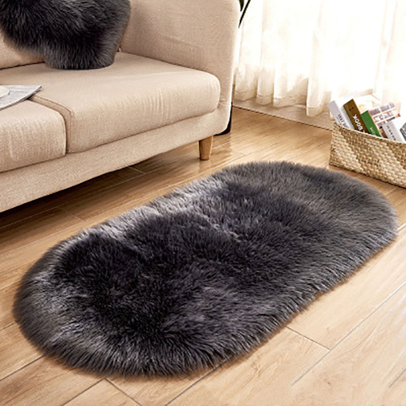 Oval wool-like carpet placed in a bedroom near the bed with cozy home décor

