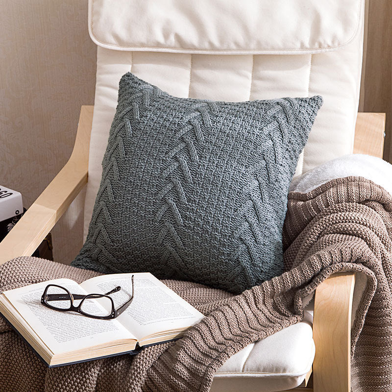 Thick wool knitted pillowcase with chunky knit pattern on a cozy sofa


