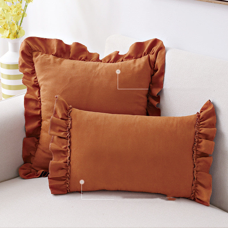 Small suede cushion pillowcase placed on a sofa beside a neutral-toned bed setup

