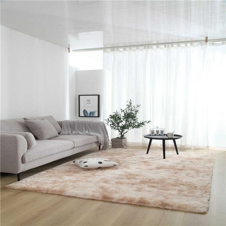 Tie-dye gradient rug with long wool texture beside a bed and end table in a modern bedroom

