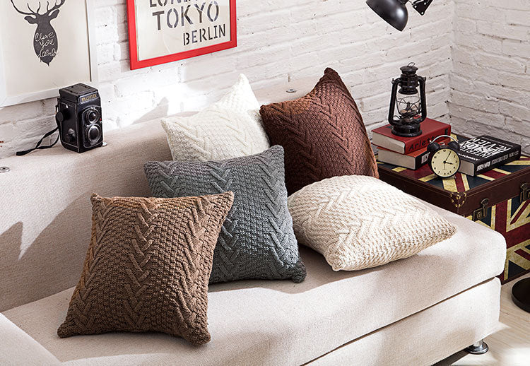 Thick wool knitted pillowcase with chunky knit pattern on a cozy sofa


