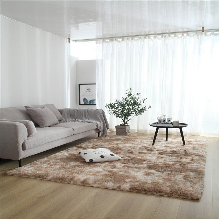 Tie-dye gradient rug with long wool texture beside a bed and end table in a modern bedroom

