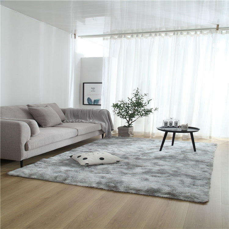 Tie-dye gradient rug with long wool texture beside a bed and end table in a modern bedroom

