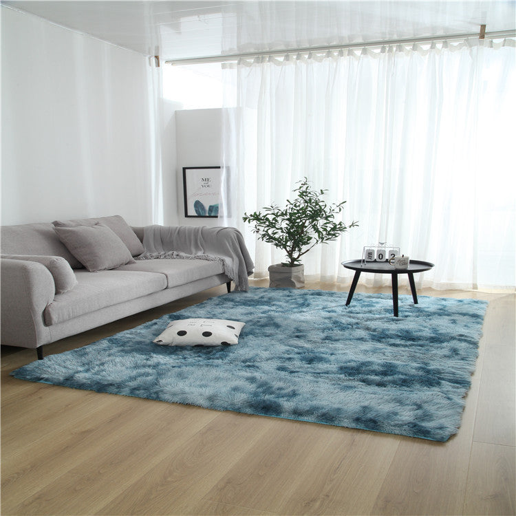 Tie-dye gradient rug with long wool texture beside a bed and end table in a modern bedroom

