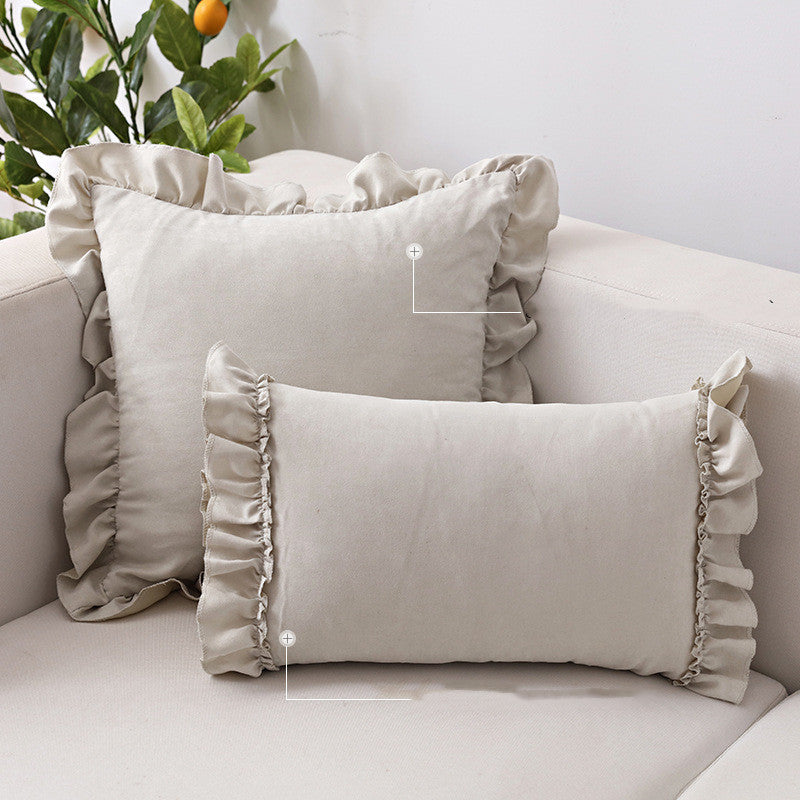 Small suede cushion pillowcase placed on a sofa beside a neutral-toned bed setup

