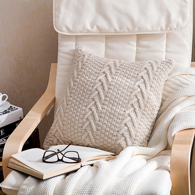 Thick wool knitted pillowcase with chunky knit pattern on a cozy sofa

