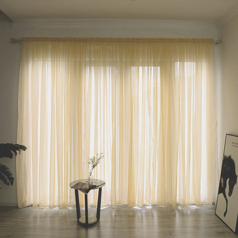 Modern solid color sheer gauze curtain on a balcony window filtering soft light

