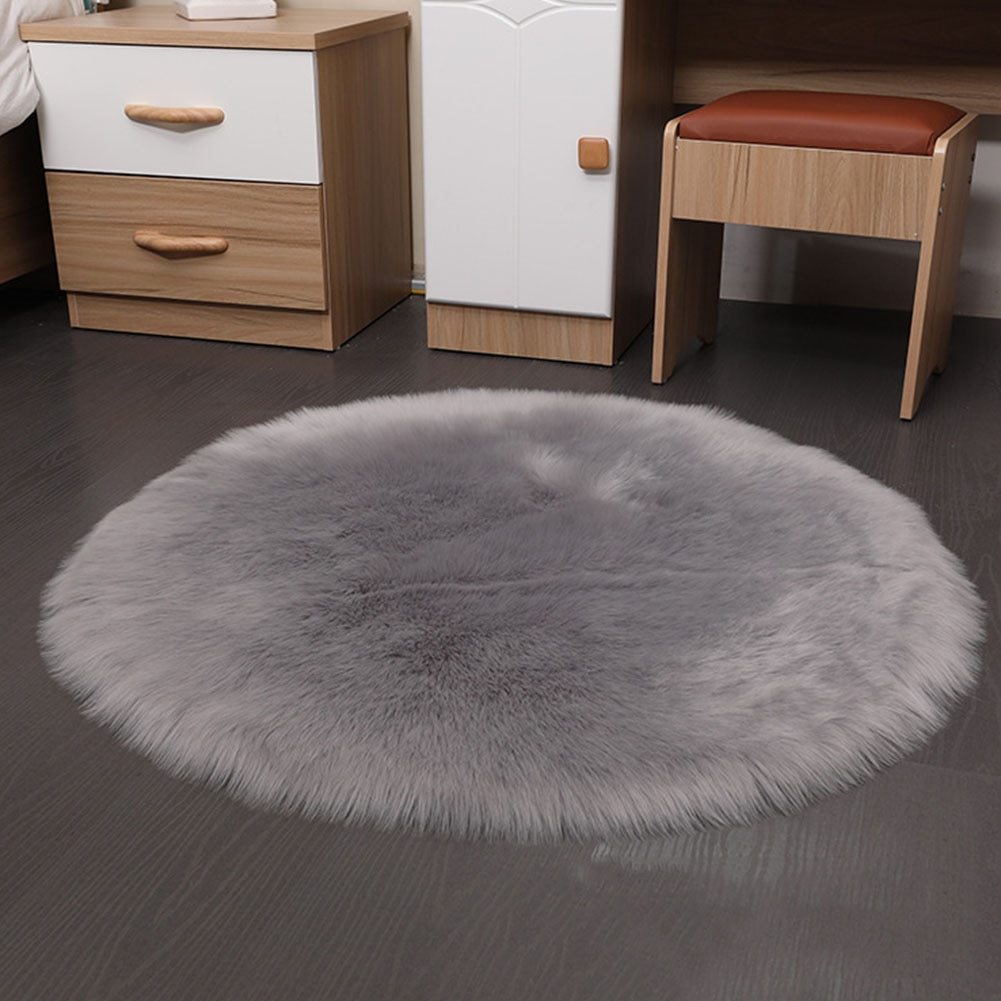 Round faux sheepskin white rug placed beside a bed on a wooden floor in a cozy bedroom

