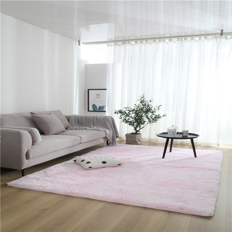 Tie-dye gradient rug with long wool texture beside a bed and end table in a modern bedroom

