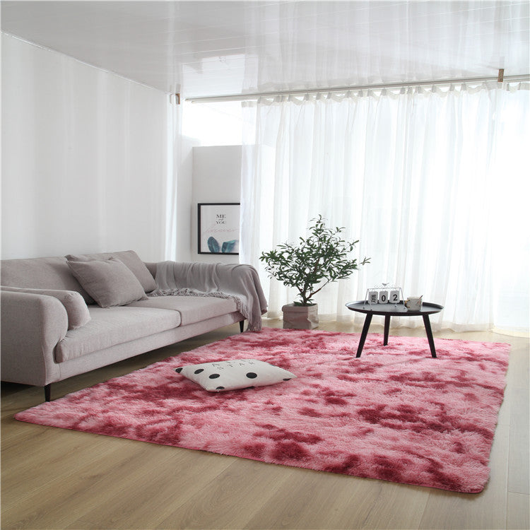 Tie-dye gradient rug with long wool texture beside a bed and end table in a modern bedroom

