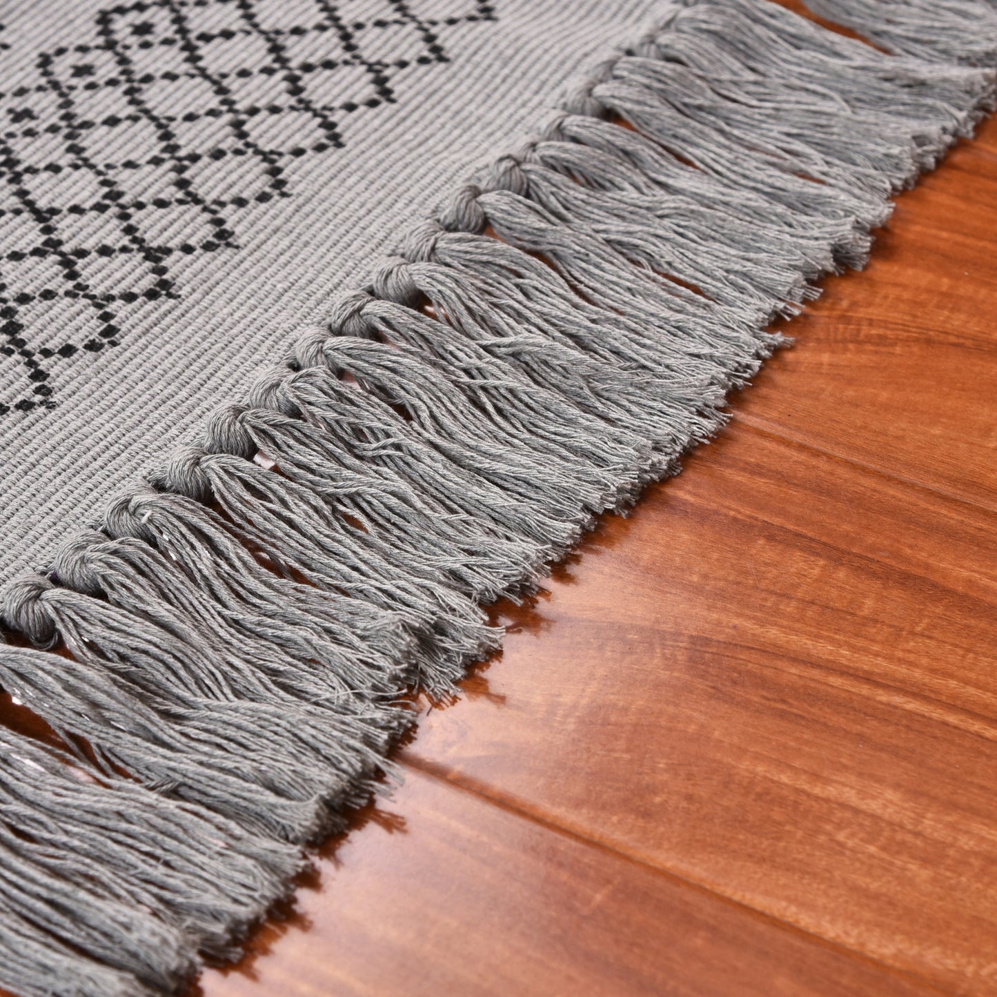 Cotton braided black printed carpet mat on a wooden floor in a minimalist room setting

