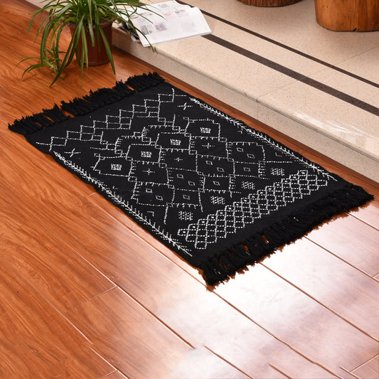 Cotton braided black printed carpet mat on a wooden floor in a minimalist room setting

