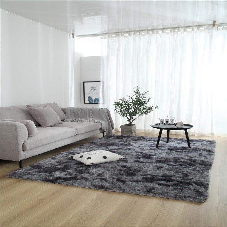 Tie-dye gradient rug with long wool texture beside a bed and end table in a modern bedroom


