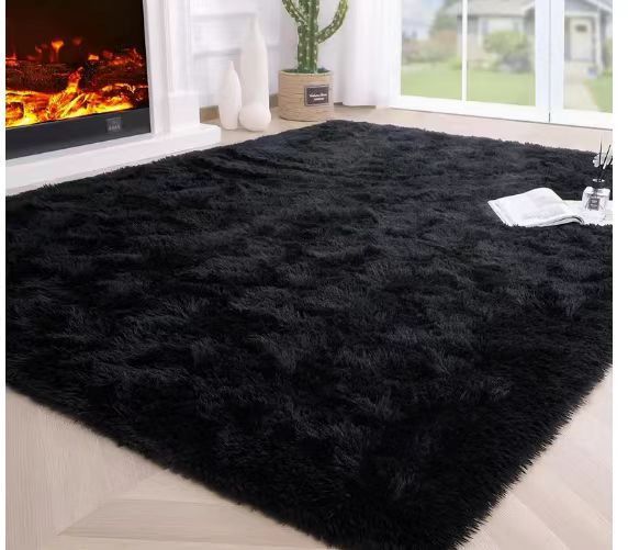 Tie-dye gradient rug with long wool texture beside a bed and end table in a modern bedroom

